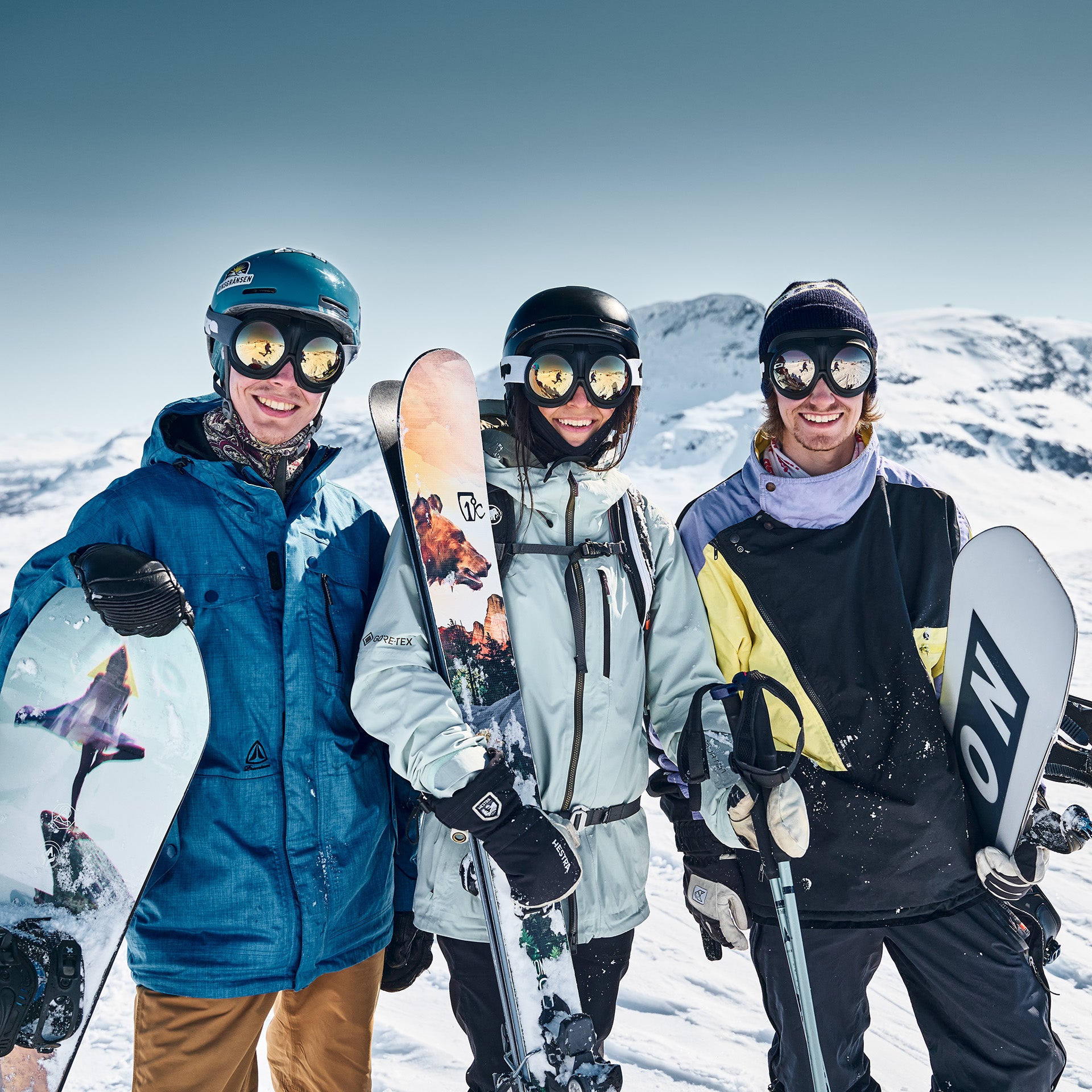 One skier and two snowboarders wearing Fluga goggles